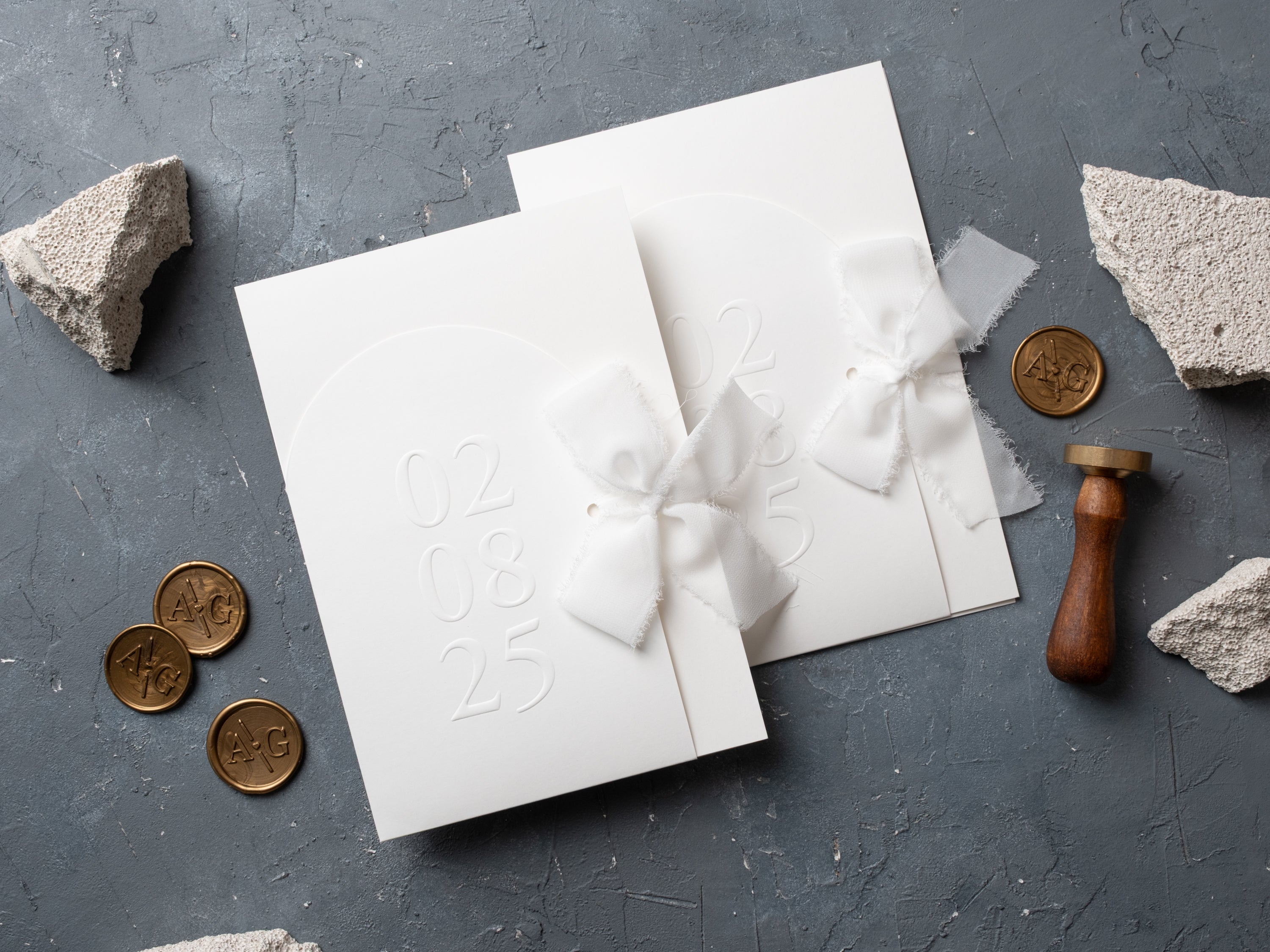 Elegant white wedding invitation set with gold wax seal and ribbon